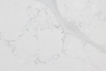 Detail of a quartz slab that has an off-white background with soft light grey veins inspired by Statuario marble