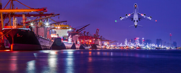 Panorama image of Container cargo ship with ports crane bridge loading dock to terminal in harbor against refinery industrial at twilight