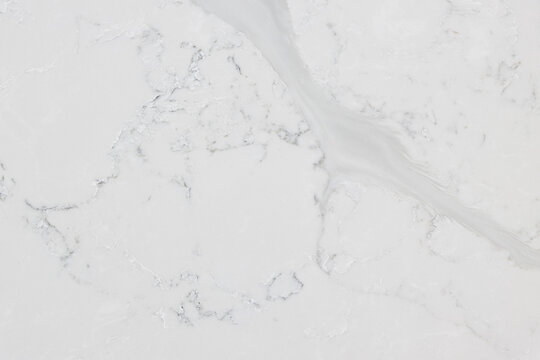 Detail of a quartz slab that has an off-white background with soft light grey veins inspired by Statuario marble