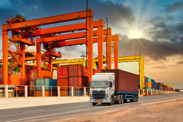 Truck container in a cargo freight ship with crane to shore lift up loading in sunset sky. import...