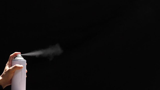 Slow motion speed closeup scene in side view of aerosol can when spraying, white color spray isolated on black background, damage ozone made green house effect problem cause of  global warming.