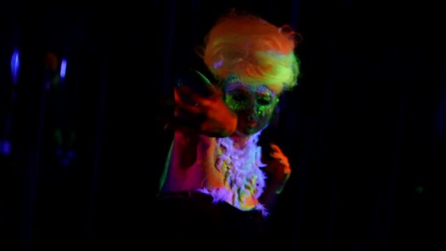 eccentric dancing woman in darkness, glowing neon makeup and hair in ultraviolet