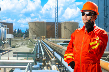 Engineer with radio communication in action for working at pipe line connection to oil tanks in...