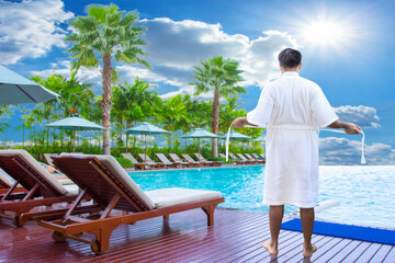 Fototapeta na wymiar man in bathrobe on edge of swimming pool and relaxing