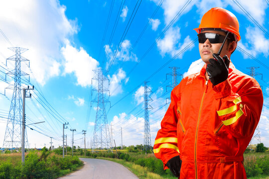 Engineer with radio communication in action for working at high voltage power pylon against blue sky