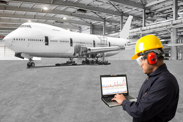 Engineer looking at laptop for maintenance an airplane are performing repairs, fixes, modernization...