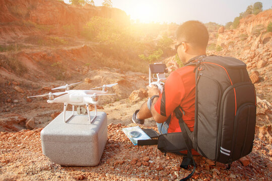 Tourist preparing for starting with drone. remote controll in hands. for taking pictures rock cliff at desert grand canyon landscape in sunrise. aerial shooting, drone videography.