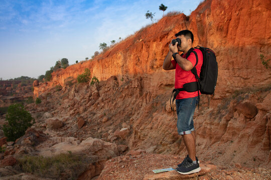 Tourist with backpack enjoying view taking pictures rock cliff at desert Grand Canyon