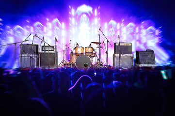 Set of musical instruments during concert with silhouettes of crowd in front of bright stage lights...