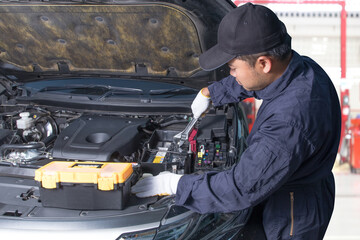 Professional Auto mechanic holding wrench for fix batterry at maintenance repair service station