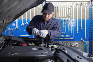 Professional car mechanic working in maintenance against garage workshop tools at repair service station