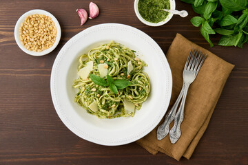 Classic Italian pesto pasta with pine nuts, garlic, basil, parmesan cheese. Rustic homemade italian causine. Delicious vegetarian green pasta. Top view horizontal