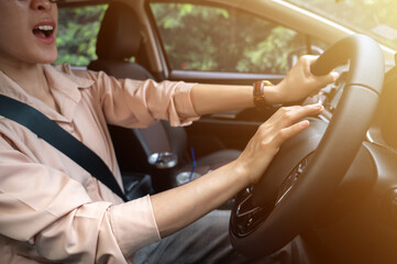 Driver pushing car horn to warn others of the vehicle's approach or presence, or to call attention...