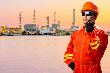 Technician with radio communication in action for working at petrochemical oil refinery in sunrise