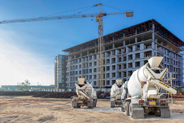 Cement mixer trucks parked standby in front of a large building under construction