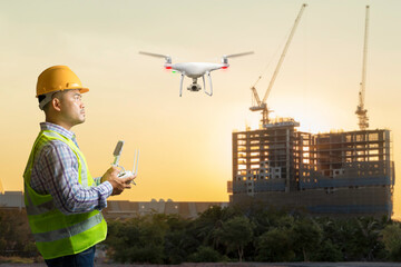 Drone operated by construction foreman for survey and checking working at high building construction site in sunset