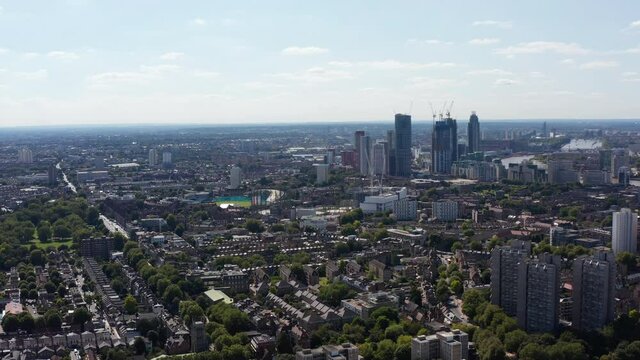 Ascending panoramic footage of large city. Housing district and tall office buildings in distance. London, UK