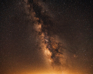 Fototapeta na wymiar Orange sky with milky way galaxy and light pollution from a distant city