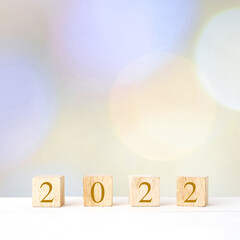 Happy New Year 2022 on wood cube block and blur abstract bokeh light background with copy space for text, Happy new year 2022 greeting card, banner