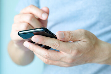 The young man's hand He is using a smartphone to connect with friends in the social network.