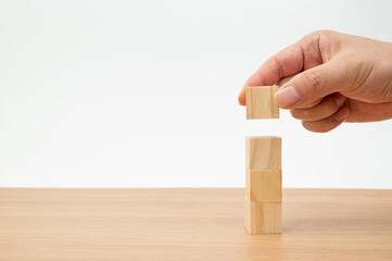 The hands of a man who is stacking wooden blocks. Business concept