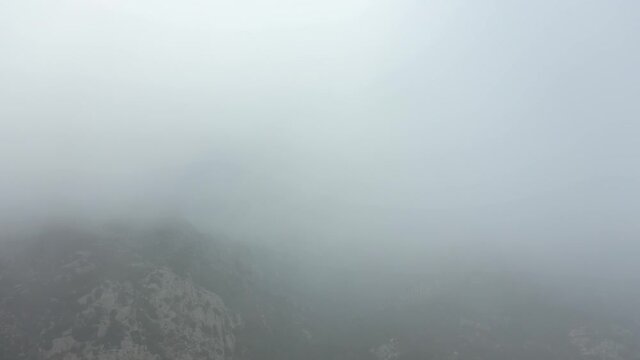 View from above, drone point of view, stunning aerial video of a drone flying over a granite mountain during a cloudy day. San Pantaleo, Sardinia, Italy.