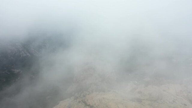 View from above, drone point of view, stunning aerial video of a drone flying over a granite mountain during a cloudy day. San Pantaleo, Sardinia, Italy.
