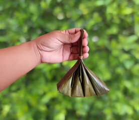 Traditional desserts of Thailand wrapped in banana leaves steamed until cooked, green background