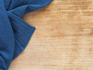 Top view, close-up of blue fabric or napkin on wooden table background. Concept kitchen utensils and tableware. Top view, flat lay with copy space..