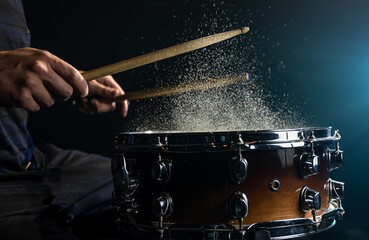 Close-up of a drummer playing a snare drum with splashing water.