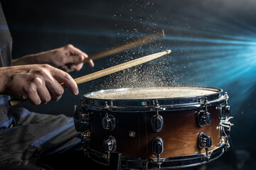 Close-up of a drummer playing a snare drum with splashing water.