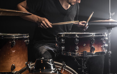 A male drummer plays drums on stage.