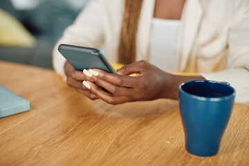 Close-up of black woman types text message on mobile phone.