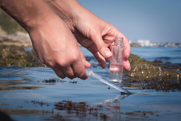 Sea water pollution concept. The scientist is taking  water sample of sea water close up concept.