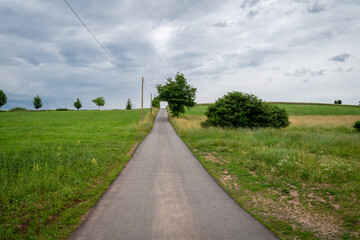 Fototapeta na wymiar Asphalted walk and bike path on a hill with cloudy sky in the countryside
