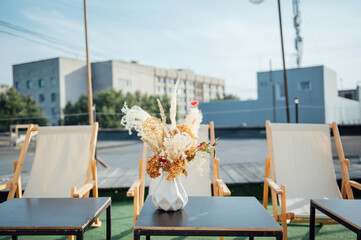 On the table is a decorative vase with dried flowers. Beautiful summer location for relaxation