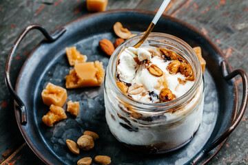ice cream with caramel sauce and nuts served in a glass jar on a blue tray, top view. place for text
