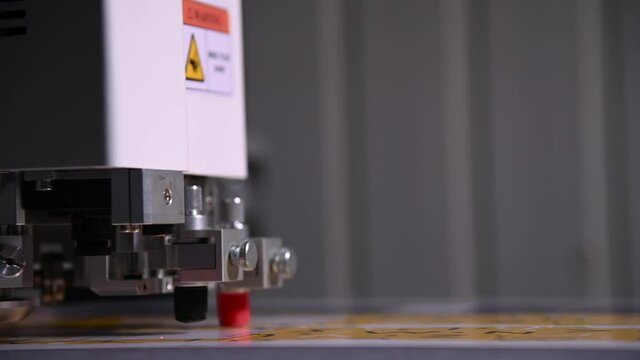 Industrial A close-up of an industrial plotter cuts a template on a cardboard packaging for products. real time shallow depth of field. Live camera