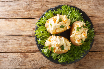 English baked potatoes topped with coronation chicken salad close-up on a slate board on the table....