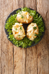 Baked potatoes stuffed with coronation chicken salad close-up on a slate board on the table....
