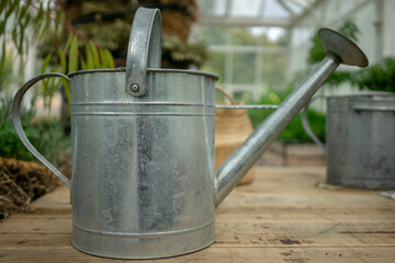 Watering can on garden bench in glass house.