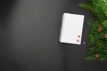 Layout on the theme of the New 2022 with a notebook,  toys and branches of a Christmas tree on a dark background.