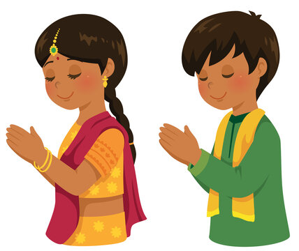 Hindu boy and girl in traditional Indian outfits praying during the Diwali festival.