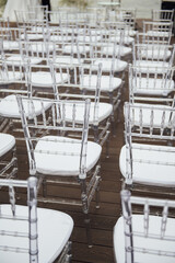 Glass chairs stand in a row in a beautiful wedding outing ceremony