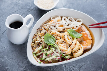 Bowl of korean traditional kuksi soup with chicken meat, studio shot on a grey concrete background, selective focus