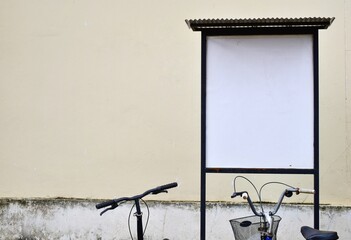 Blank billboard with cream-colored wall background with bicycles parked.