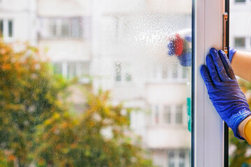 A person sprinkles a cleaning agent on the window on a sunny day.