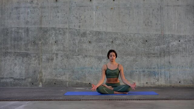 Calm caucasian woman sitting in lotus pode meditating and feeling harmony after physical poses and training, pensive female concentrated on mind and thoughts during relaxation
