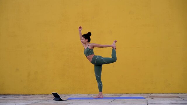 Video of caucasian sportswoman in tracksuit trying to replicate poses during training watching online tutorials on digital tablet, newbie female practice yoga using touchpad application

