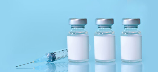 Three vials with a vaccine, a syringe on a blue background.The concept of medicine, healthcare and science.Coronavirus vaccine.Copy space for text..Banner